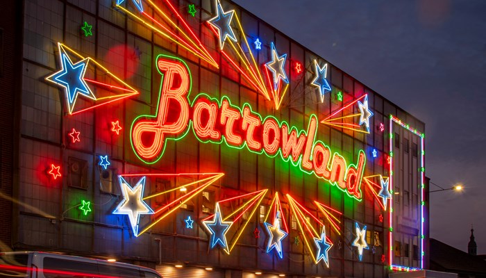 The Barrowlands sign lit up in multi-coloured lights at night time.