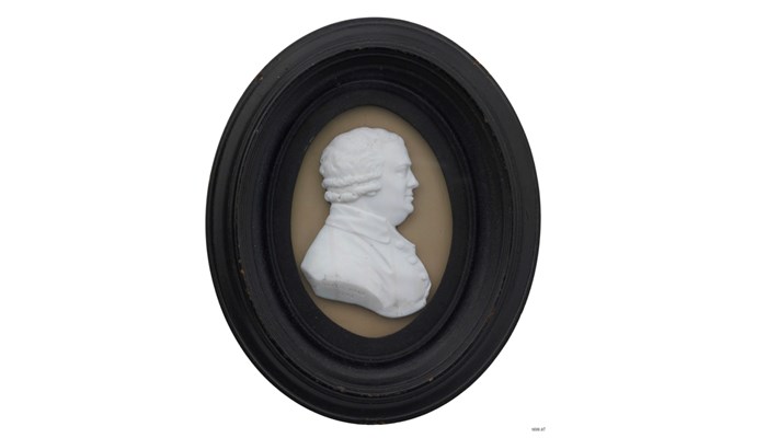 a bas-relief medallion in white stone on a tan and black frame of David Dale