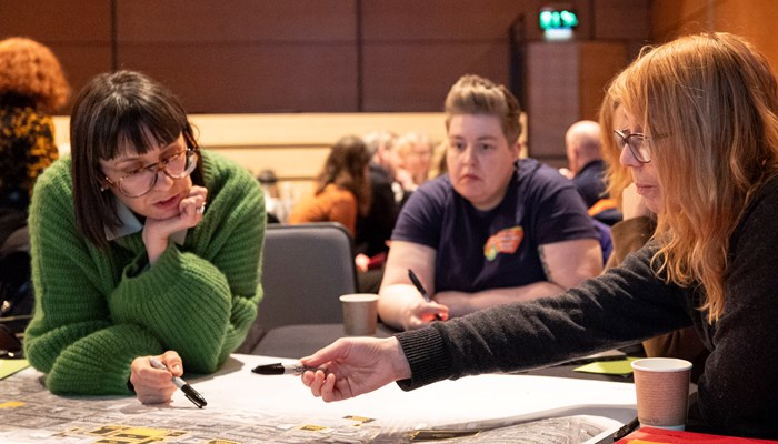 Three people discussing and writing down their ideas for Sauchiehall Street at a workshop.