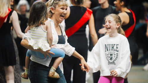 An adult and two children smiling and dancing at Merchant Square in Glasgow.