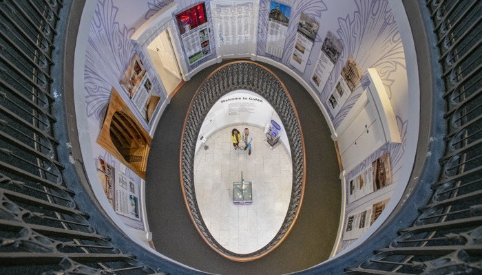 Aerieal view from top of GoMA. The central staircase drops to the floor as we see 2 visitors chatting on the ground floor.