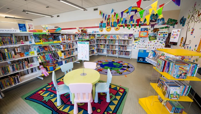 Very colourful children's tables and chairs with bunting, standalone bookshelves and wall art