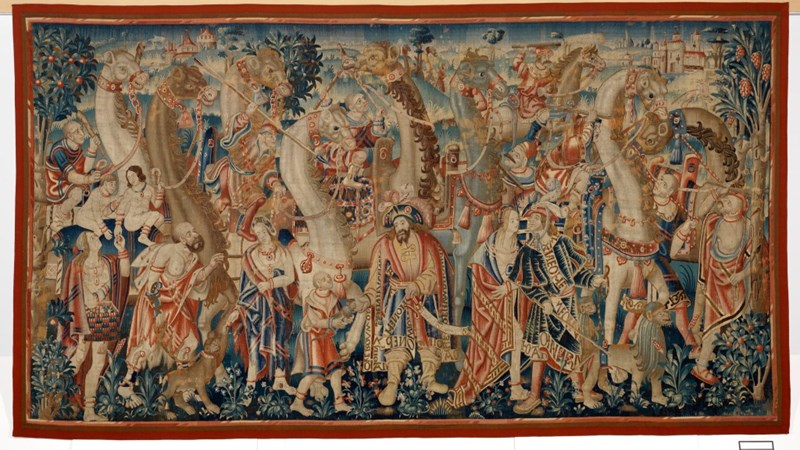 large colourful tapestry showing dozens of people and animals tightly packed into the piece