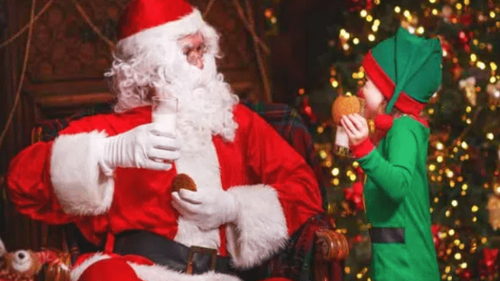 Young child in elf costume meets Santa