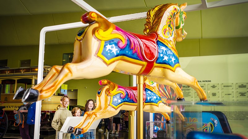 Photograph showing a young family inside Riverside Museum looking at a display of a carousel horse