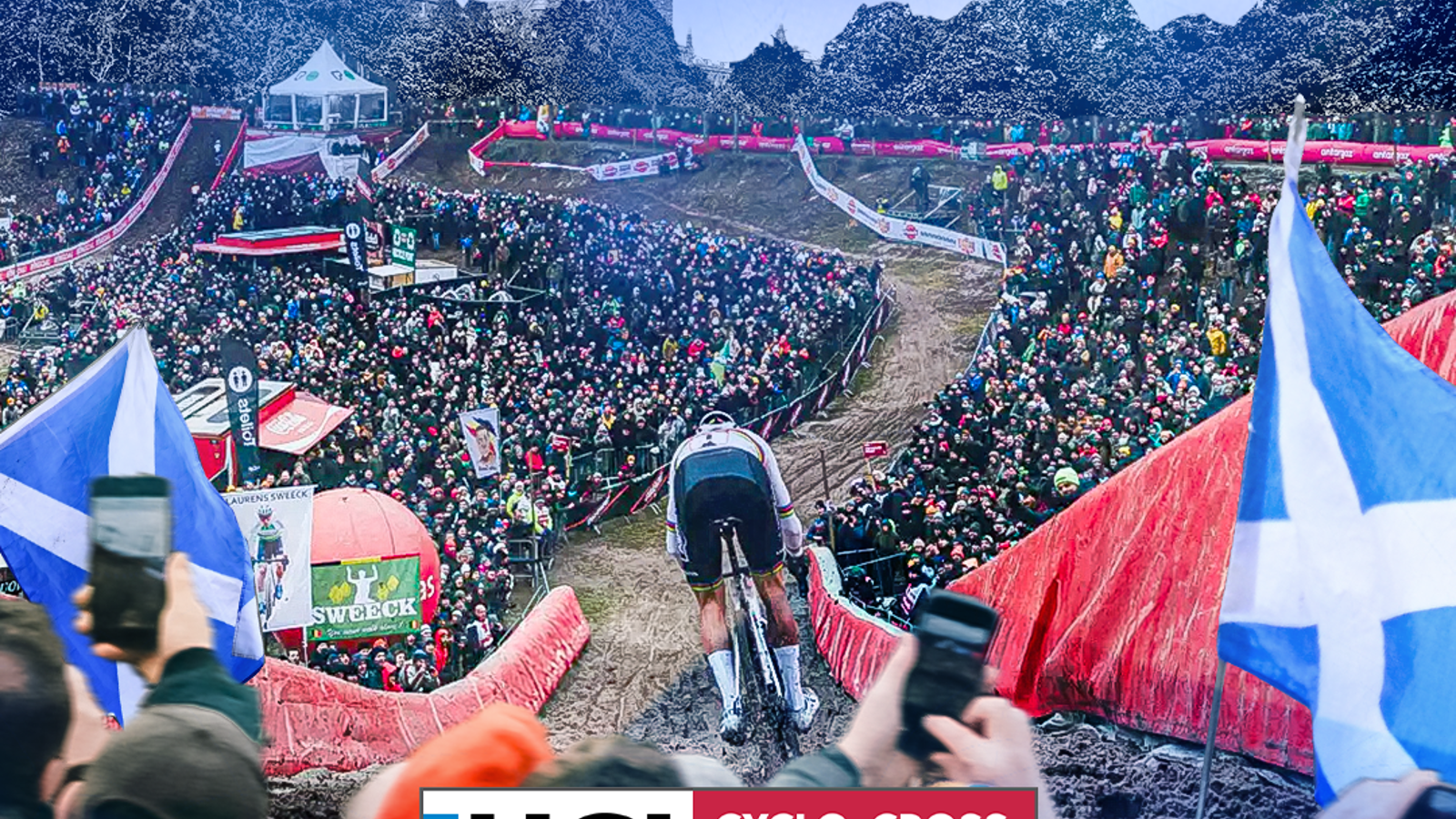A cyclist races down a cyclo-cross track in front of a large crowd
