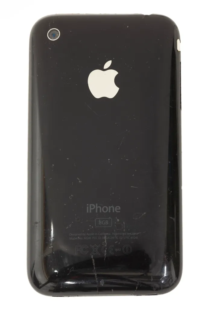 a photograph of an original iPhone on a white background. The apple logo is visible on the rear.