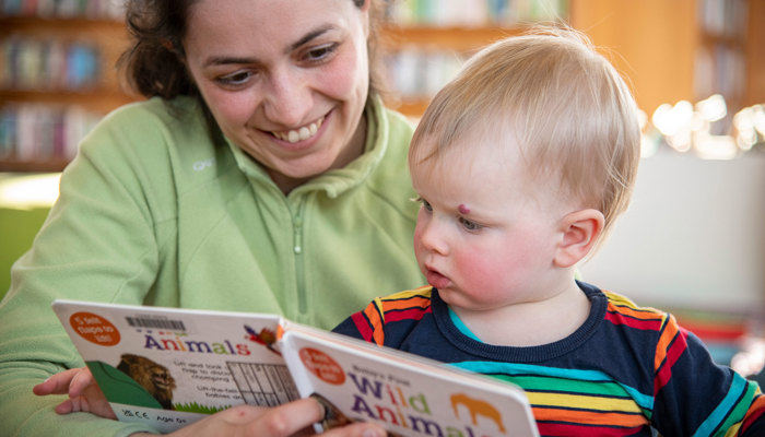 Adult reading from a picture book about wild animals to a small child