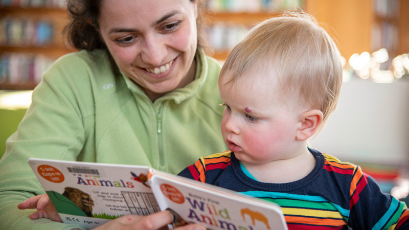 Adult reading from a picture book about wild animals to a small child