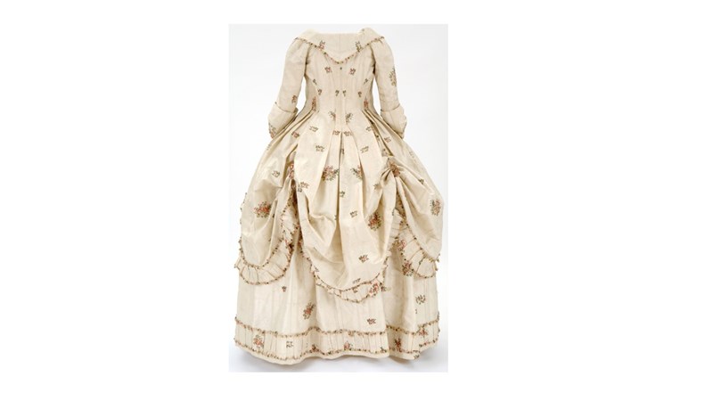 an image of a long cream dress with brown spotty patterning on the front.