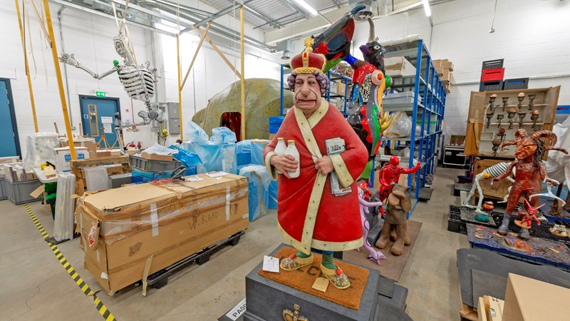 Photograph showing a humorous interpretation of a sculpture of HM Queen Elizabeth II with a whole collection of objects in the background.