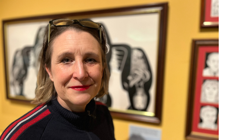 woman stands in front of paintings in a gallery setting