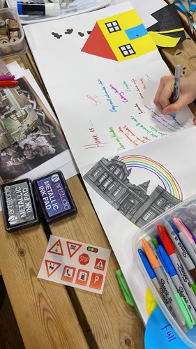 A hand draws on paper they are drawing brightly coloured houses.