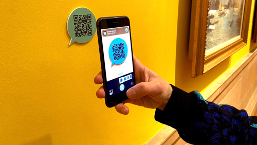 Photograph showing someone's hand using their phone to access My Stories Lite in Kelvingrove Art Gallery and Museum