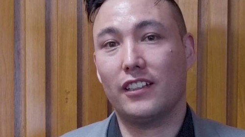 Male with black hair wearing a suit jacket and black shirt