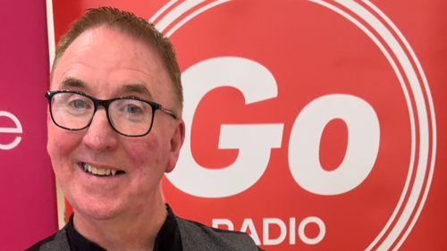 A singer wearing a grey waistcoat opens a golden envelope after winning Glasgow Life's A Song for Glasgow competition