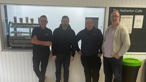 Four people standing in front of the serving area of a cafe in a community centre