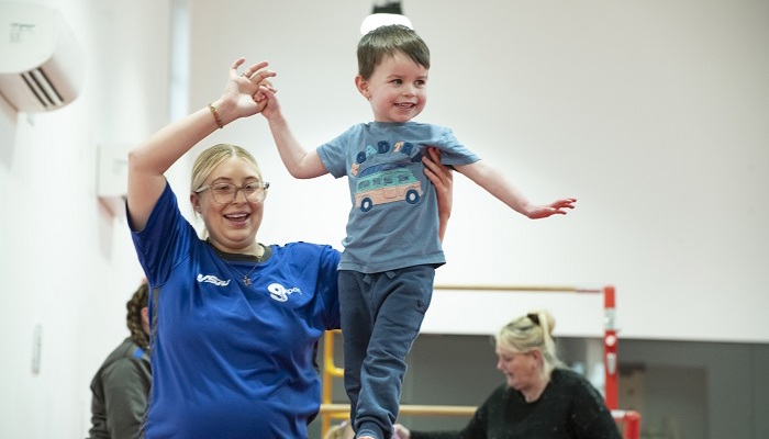 A gymnastics instructor helping a child to balance on a beam