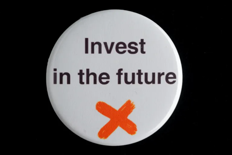 photo of a plastic badge with the words "Invest in the future" written on it.