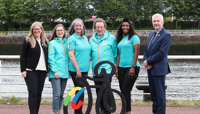A group stood at a riverside, most of whom are wearing a turquoise kit which will be worn by volunteers at the UCI Cycling World Championships in Glasgow and across Scotland