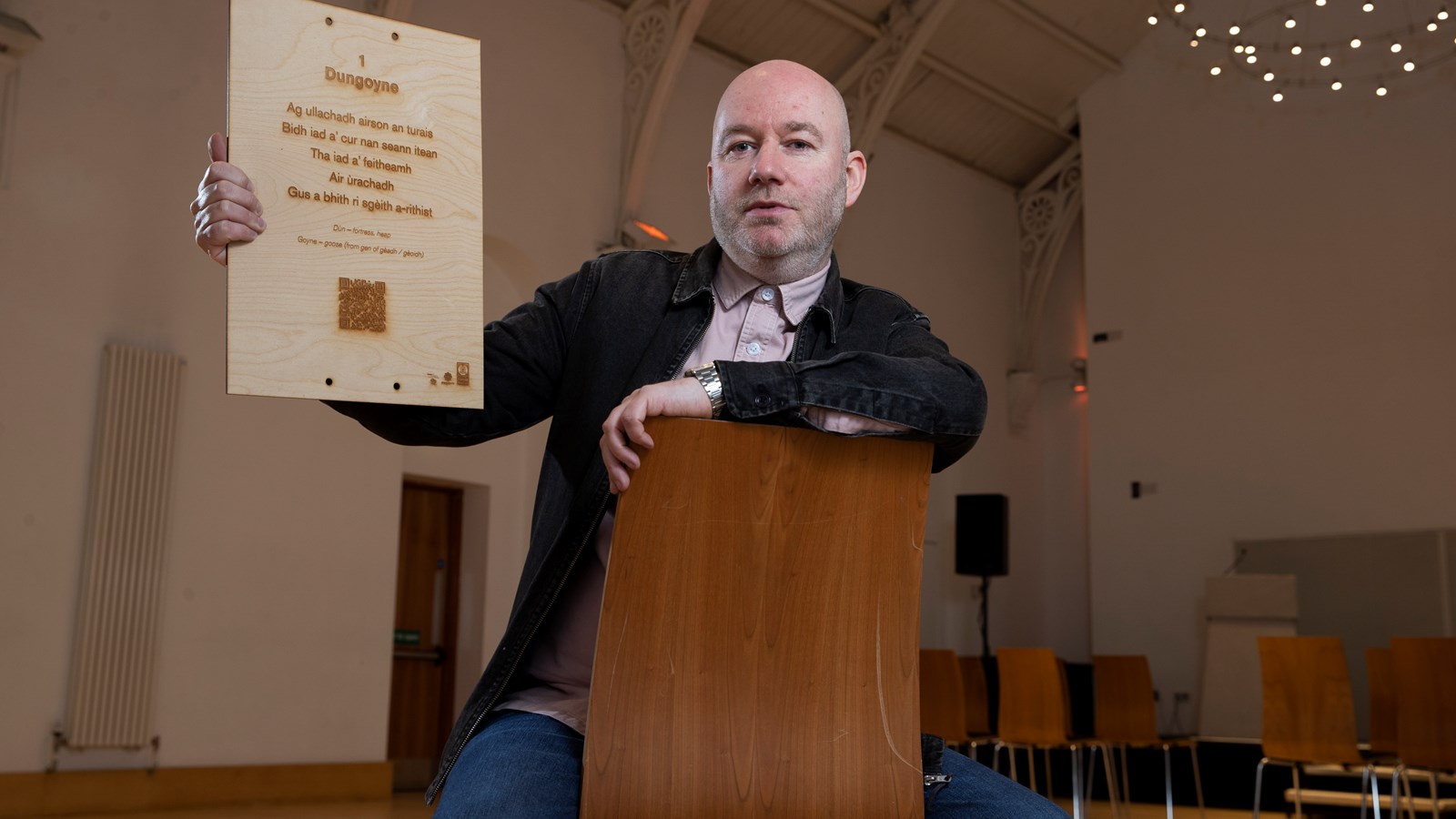 Artist Martin O'Connor poses with a plaque from a Gaelic poetry trail