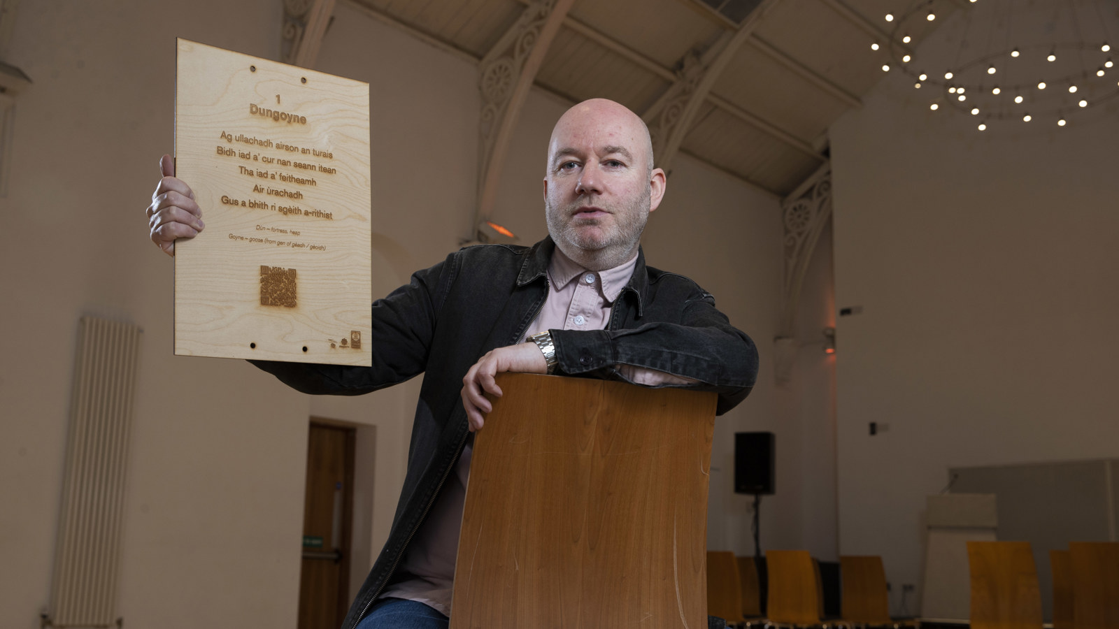 Artist Martin O'Connor poses with a plaque from a Gaelic poetry trail