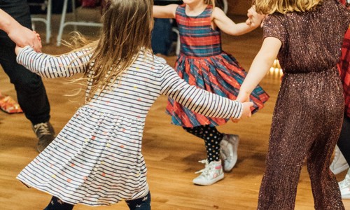 A group of children dance in a circle