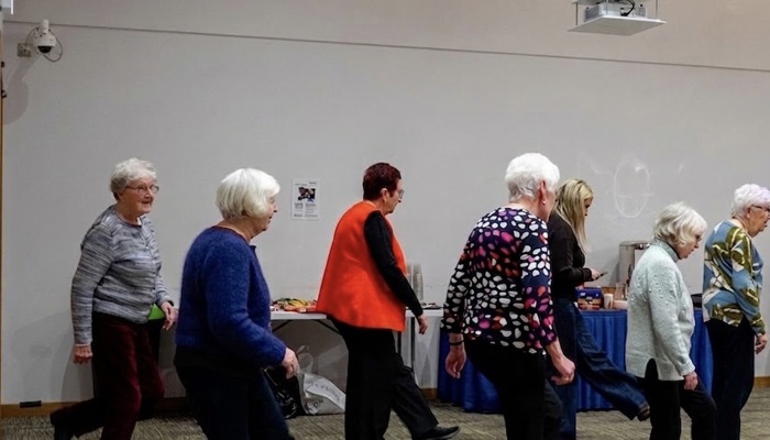A group adults are up dancing at a community event. 