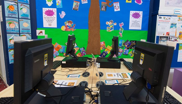 Children's PC area with 4 computers facing each other. On the wall beside them there is home-made children's tree artwork