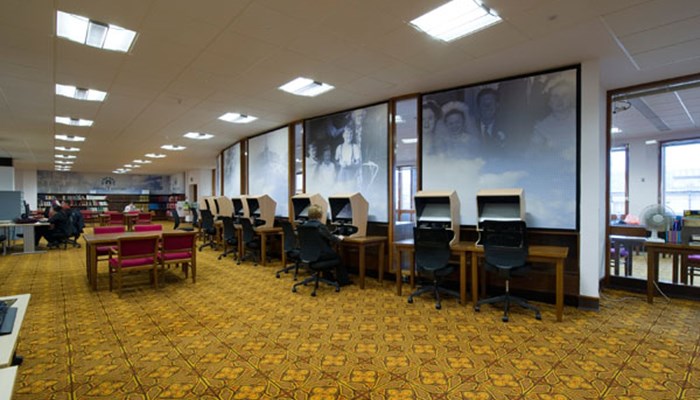 A photo of the special collection department which includes pine tables, red chairs, computers and books.