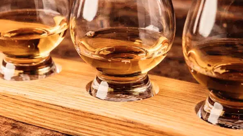 Three drams of whisky shown on a wooden serving board