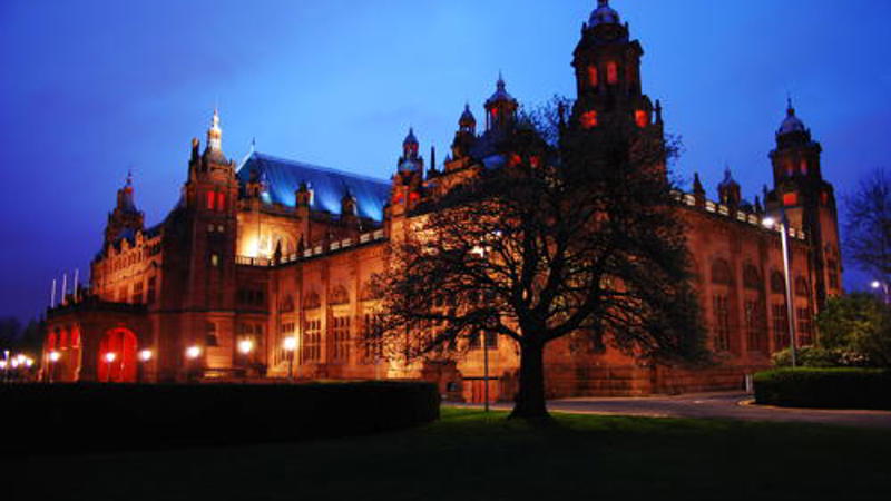 Exterior view of Kelvingrove Art Gallery and Museum in Glasgow in the evening with a dark blue sky.