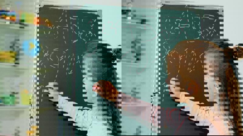 A child writing numbers on a board in a classroom