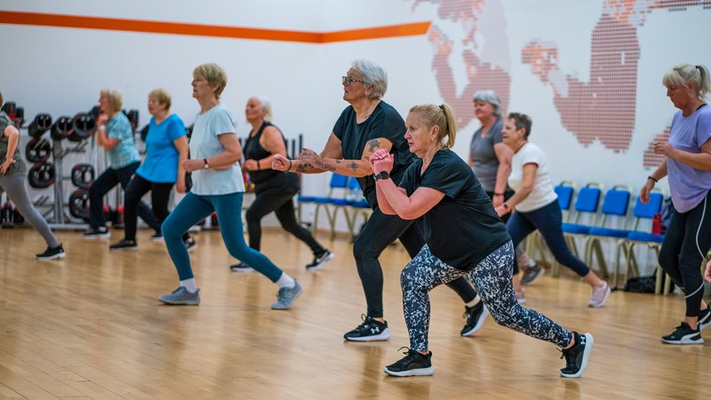 group of women of different ages in a sport hall participating in a group exercise session