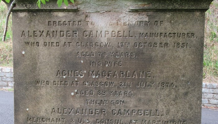 Alexander Campbell's headstone that has some stonework wearing away at the bottom and a graveyard path in the background.