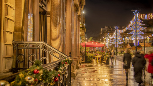 Pavement on George Square at night with people walking and Christmas lights in the background