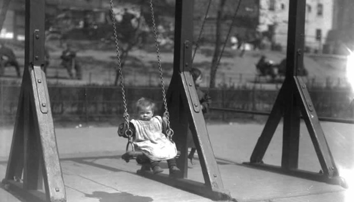 Black and white photograph showing a small toddler on a swing