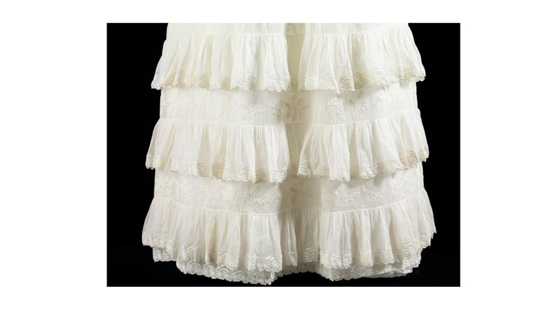 a detail shot of the frills at the bottom of a long white dress