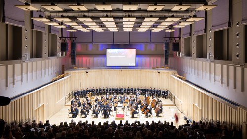 an orchestra playing on stage in a concert hall with seating all around