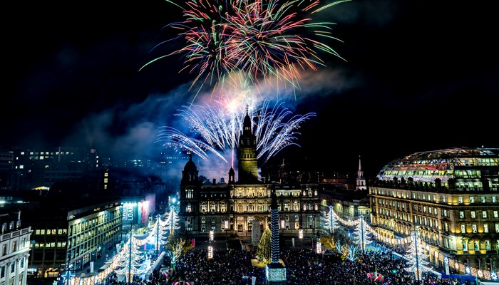 Christmas lights are lit up in Glasgow's George Square as red, green and blue fireworks are set off above Glasgow City Chambers
