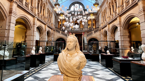 Photograph showing a head and shoulder sculpture of Queen Victoria with a view of the Life gallery inside Kelvingrove Museum