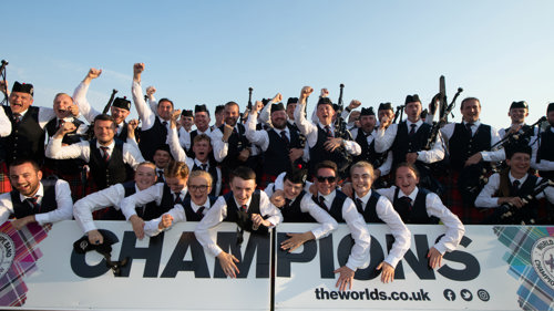 champions Field Marshal Montgomery Pipe Band celebrating their 2023 winners moment with happy faces in front of the World Pipe Band Championships CHAMPIONS board in Glasgow Green