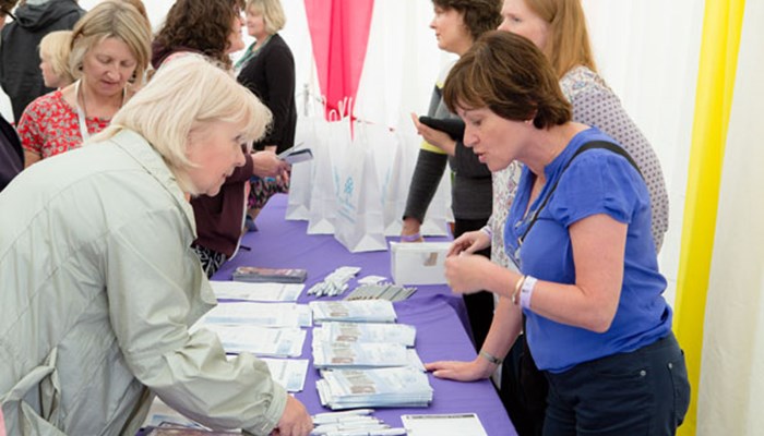 Several library staff at a Family History stall answering questions and giving out leaflets to members of the public.