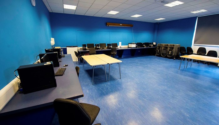 room with blue walls and a blue floor with desks and computers positioned around the room