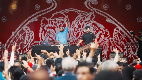 Musicians in the background acknowledge a busy crowd of festivalgoers