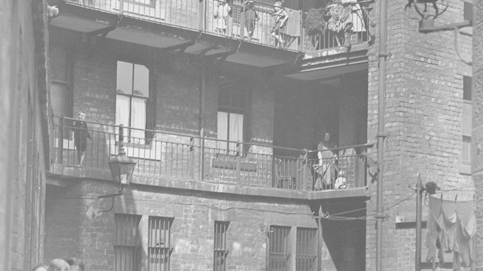 A black and white photograph of a model dwelling house in King Street, Glasgow, with children playing in the courtyard and adults watching overhead from the verandas.