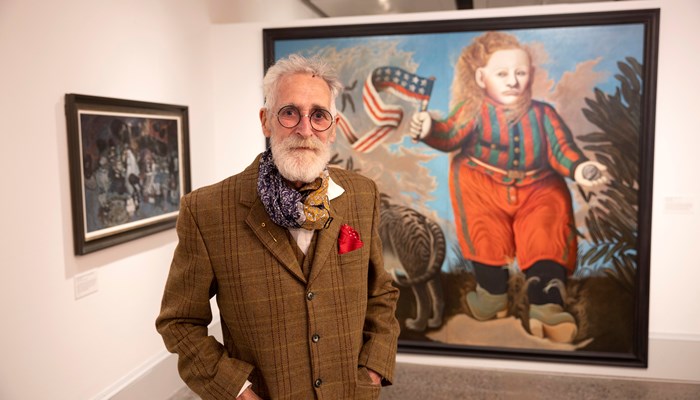 John Byrne wearing glasses in front of painting