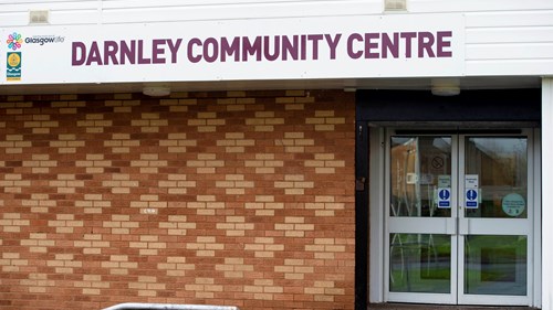 red brick wall with the words darnley community centre printed on a white sign above the door