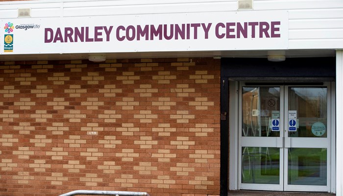 red brick wall with the words darnley community centre printed on a white sign above the door