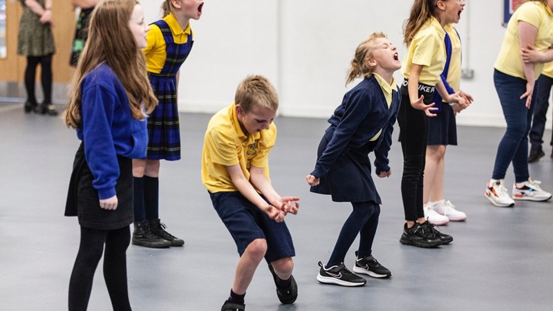 A group of children pull dramatic faces and poses in a drama session